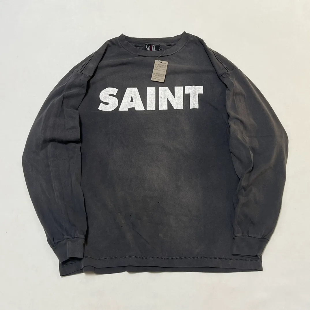 SAINT Mxxxxxx S>N>T LS TEE/BLACK Autumn and winter new style S>N>T slogan crack printed long TEE, washed black S-XL Asut ready-made garments dyed, the whole piece sprayed with horse-hair spray, and then sprayed again to fade the color. The collar and cuffs are frayed. Many hangings are worn NEW VINTAGE. Heavy craftsmanship.